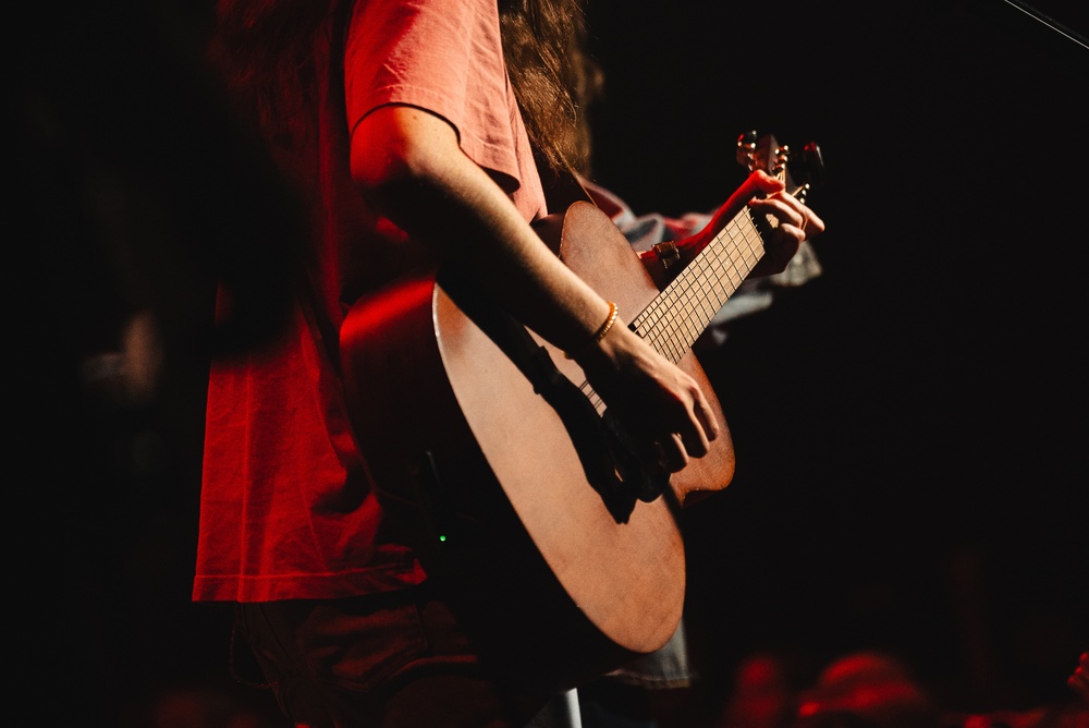 Woman,Playing,Acoustic,Guitar,On,Stage,Under,Red,Light